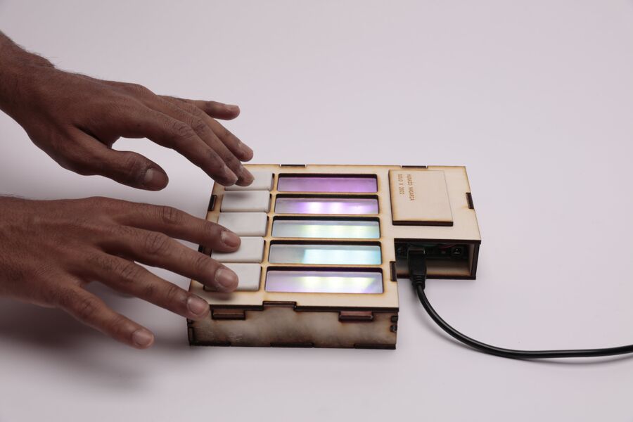 Photo of a person's hands gently touch a small electronic box with coloured lights, showcasing interaction with technology
